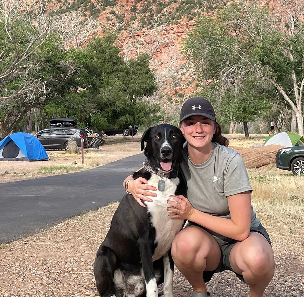 P.E.A.S.E. Academy teacher sitting next to dog in campground.